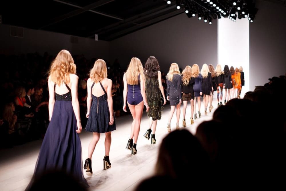 several models walking down a lit up runway