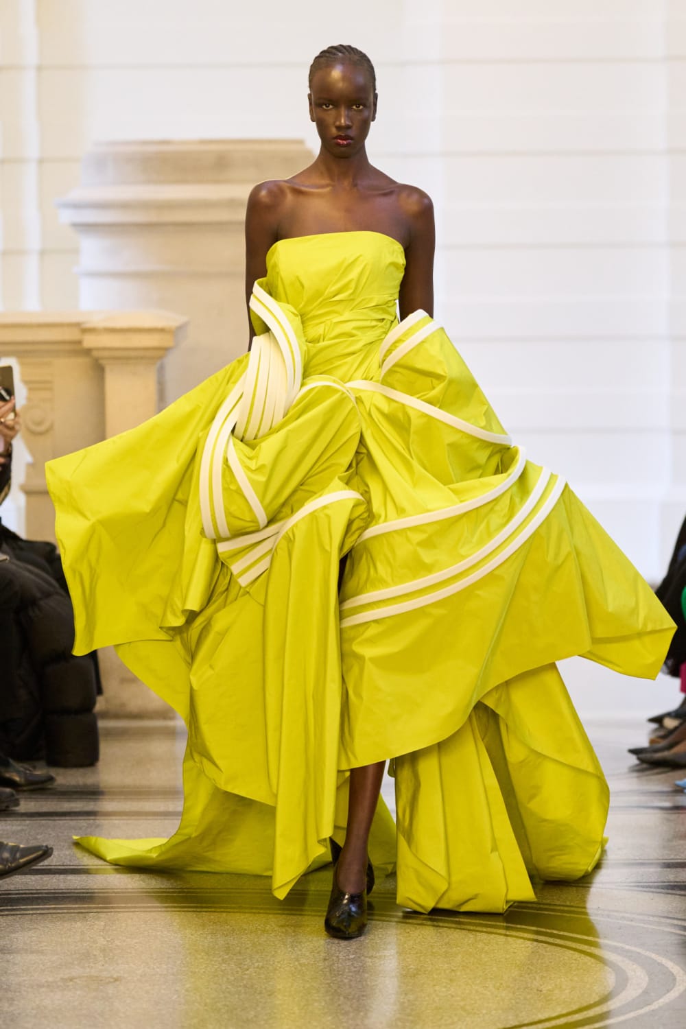 Woman walking down a runway in a neon yellow Roksanda dress