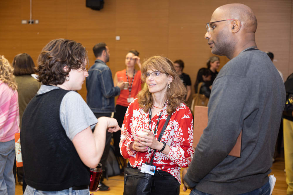 Three people stand in a circle chatting. 