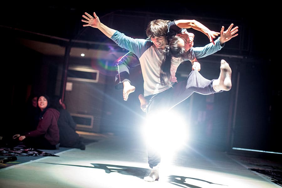 Two people dancing on a stage; the man holding the woman on his back.