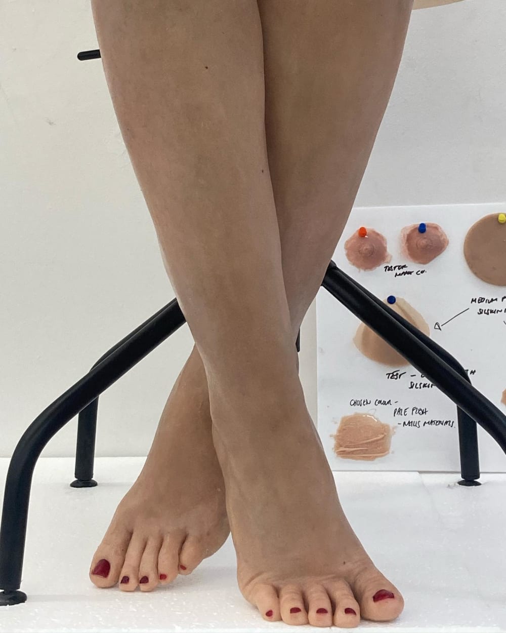 Silicone sculpture of legs and feet on figure with painted details.