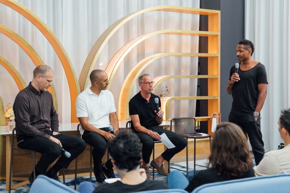 Speakers sitting at the front of the room, with Bruce Reynolds standing next to them 
