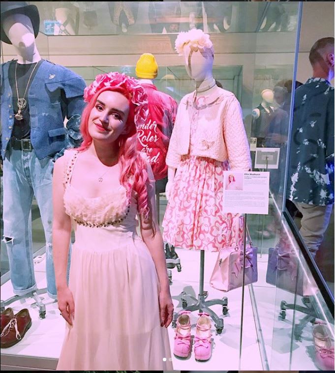 Women in pink in front of pink ensemble on display in Brighton Museum