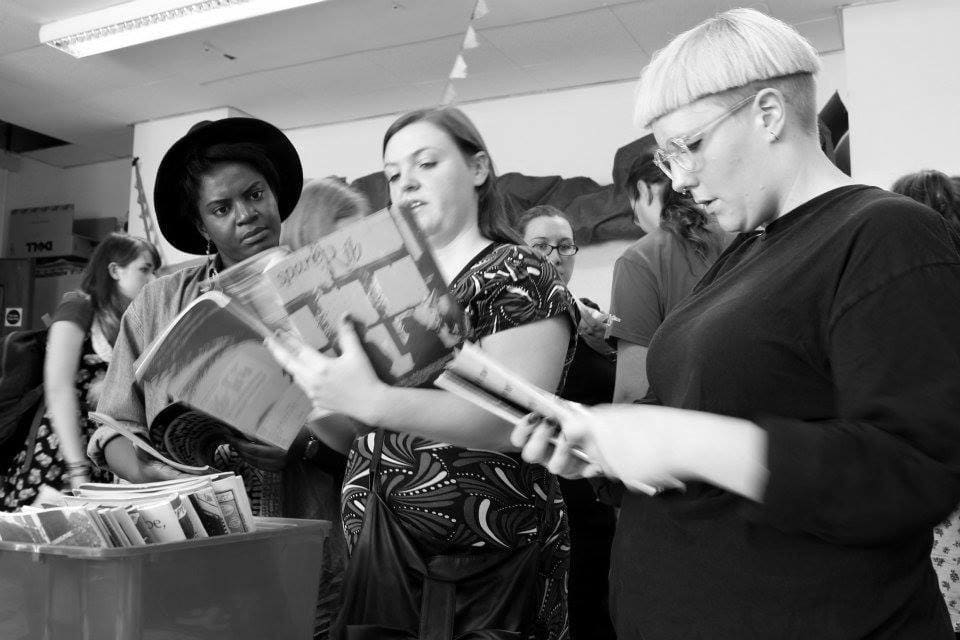 three people looking through magazines
