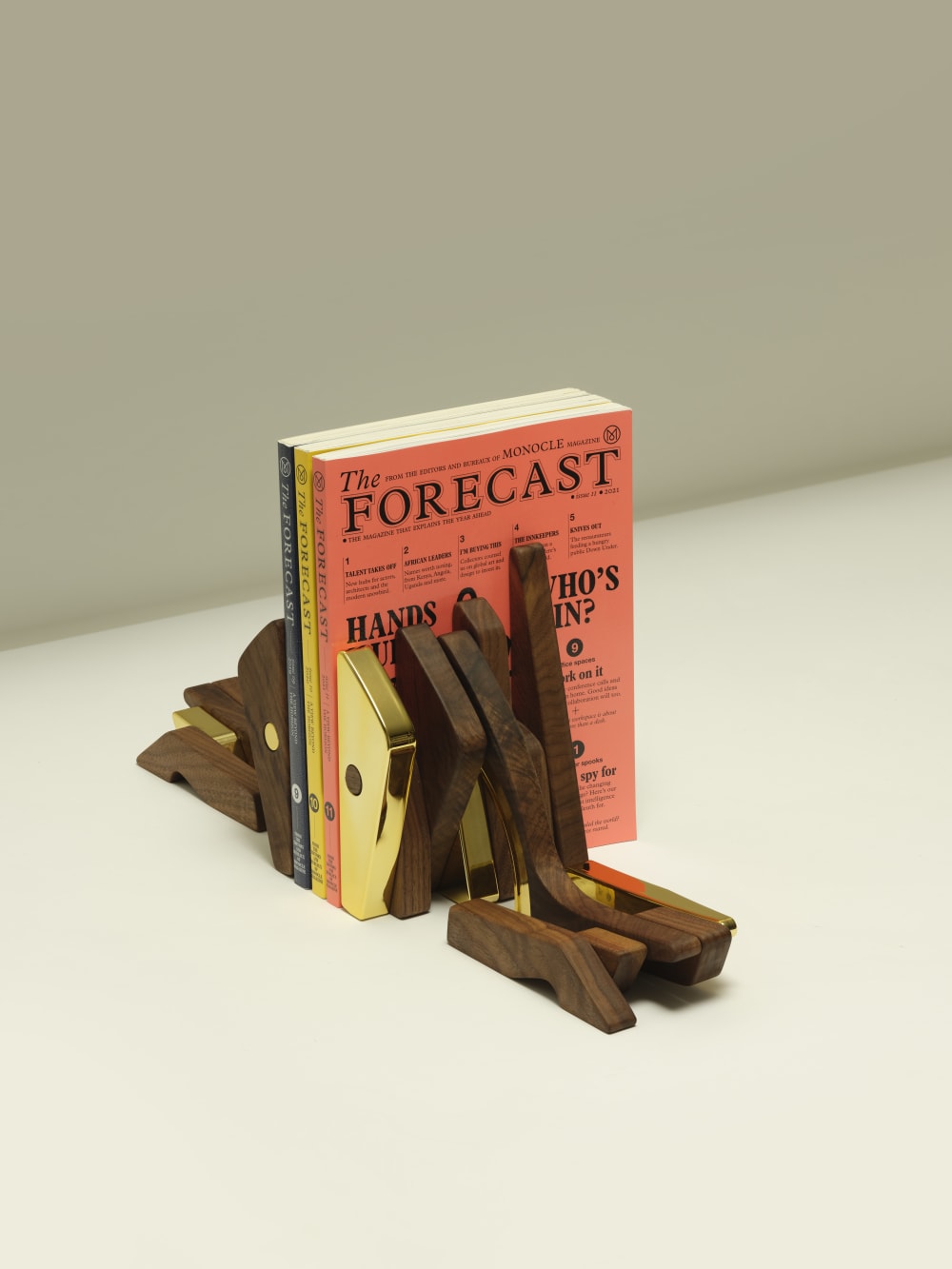 Two wooden and golden shoes positioned as bookends around three colourful books. 