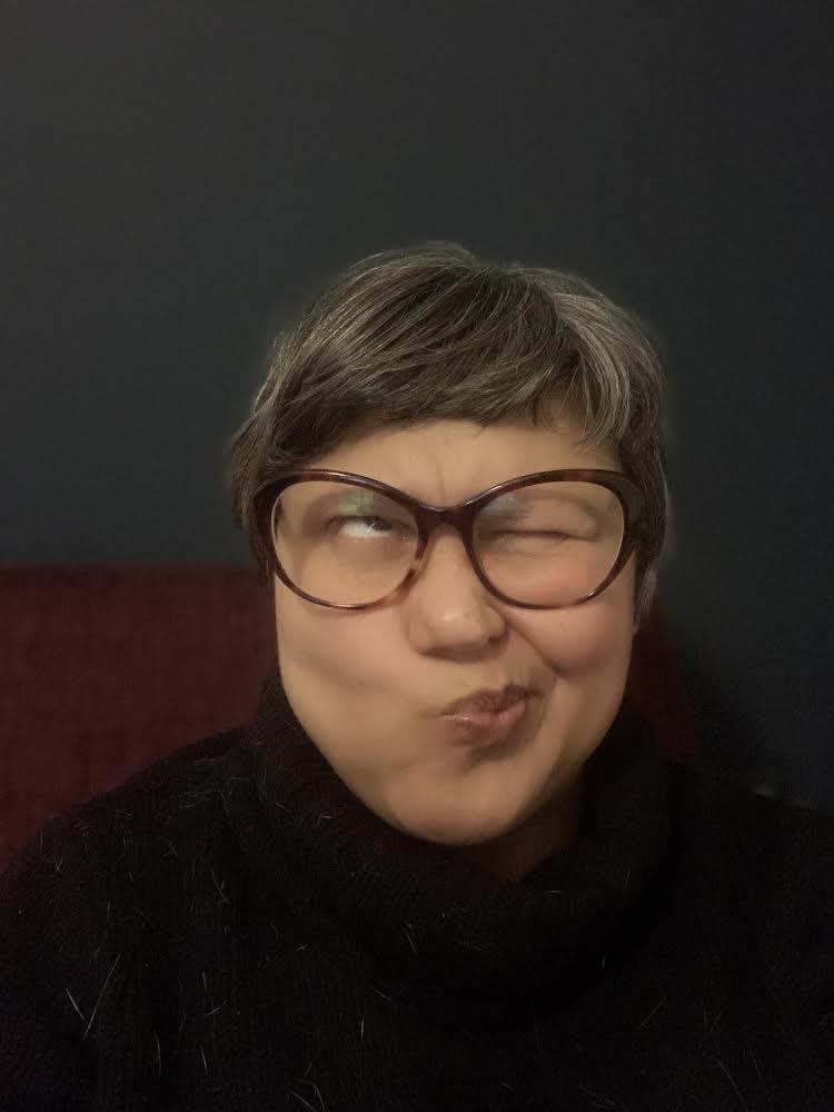 Close up of Tina with a fringe and glasses pulling a silly face