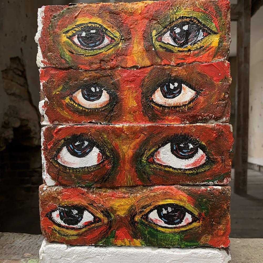 Acrylic on bricks, paintings of eyes onto bricks, which are stacked up