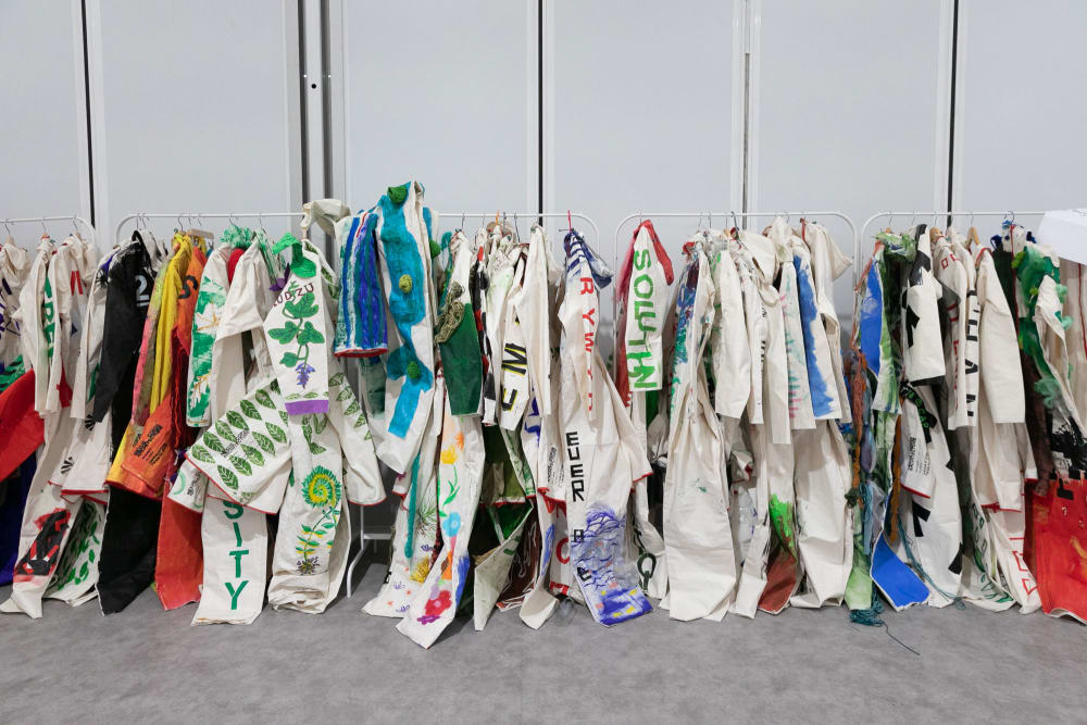 A row of lots of boiler suits hanging up, each one differently customised with colour, printing  and text.