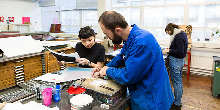 A technician assisting a student with ink mixing in the Letterpress workshop.
