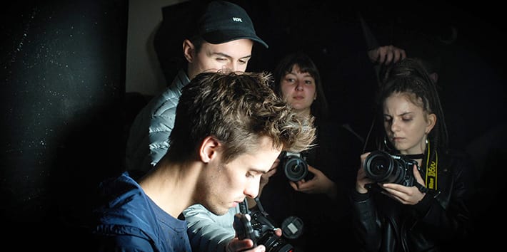 A group of students operating cameras in a darkened studio.
