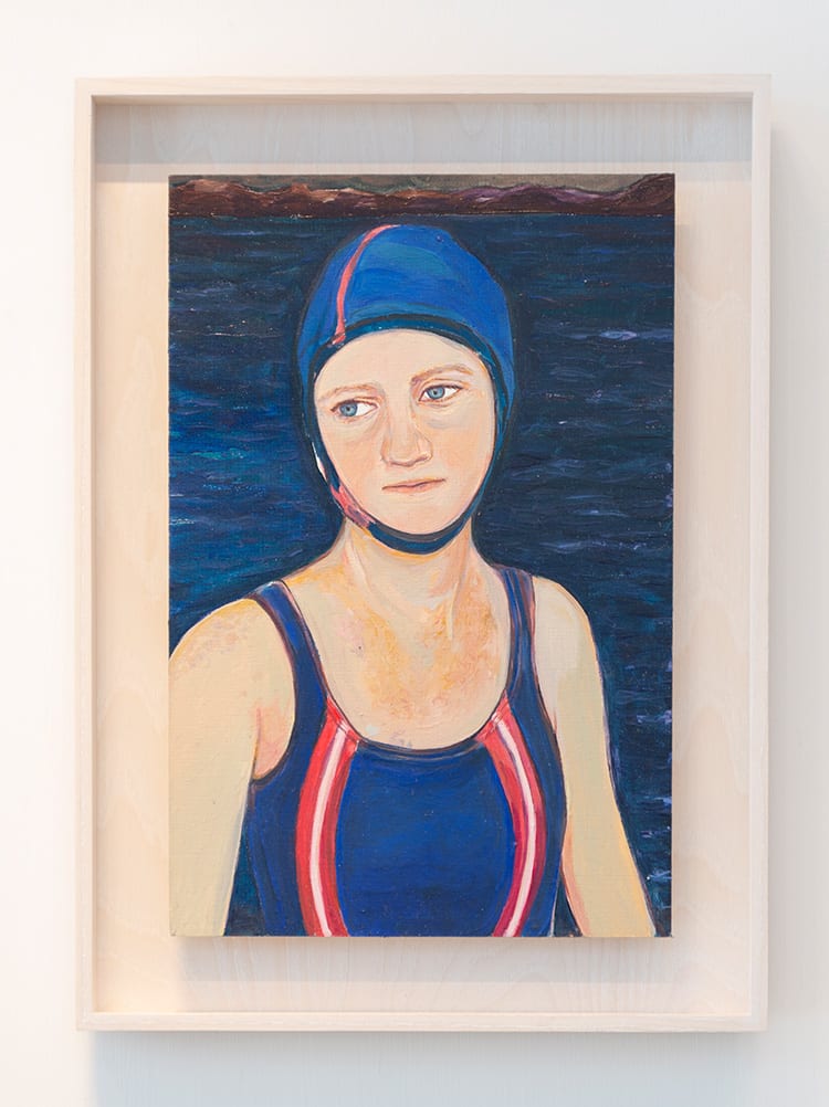 Portrait of a person in a swim cap and swimsuit. They're looking off to the left