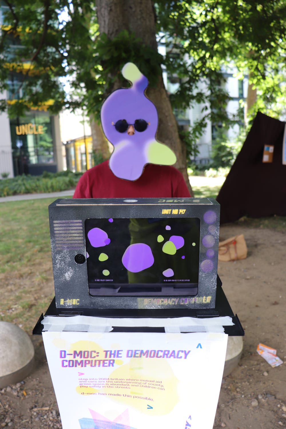 a person wearing a purple mask behind artwork