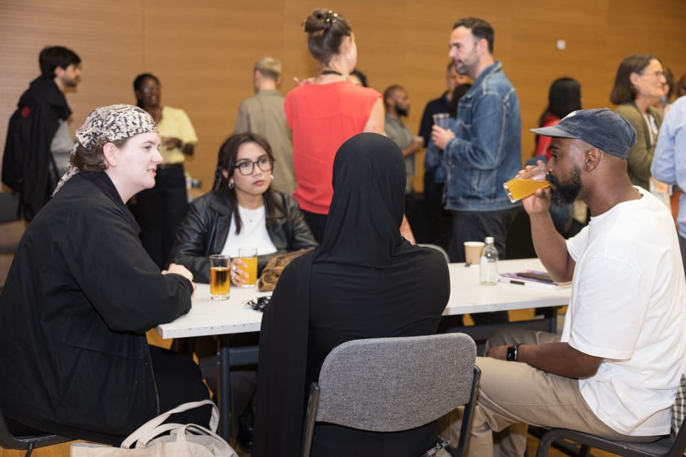 Three people sit around a table with drinks and cake