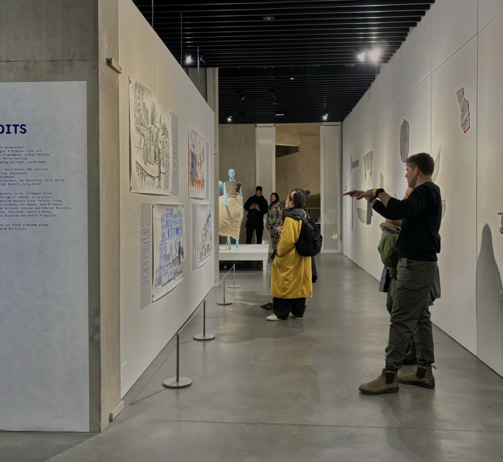 Two people in a gallery looking at drawings.