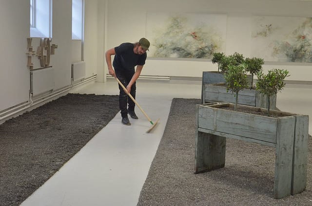 An image of the artist in the studio raking stones into neat lines.