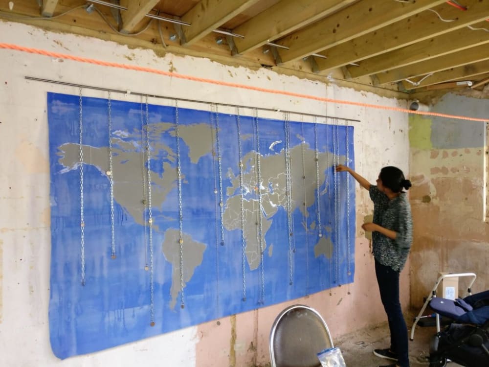 A person standing on a stall creating a map on the wall.