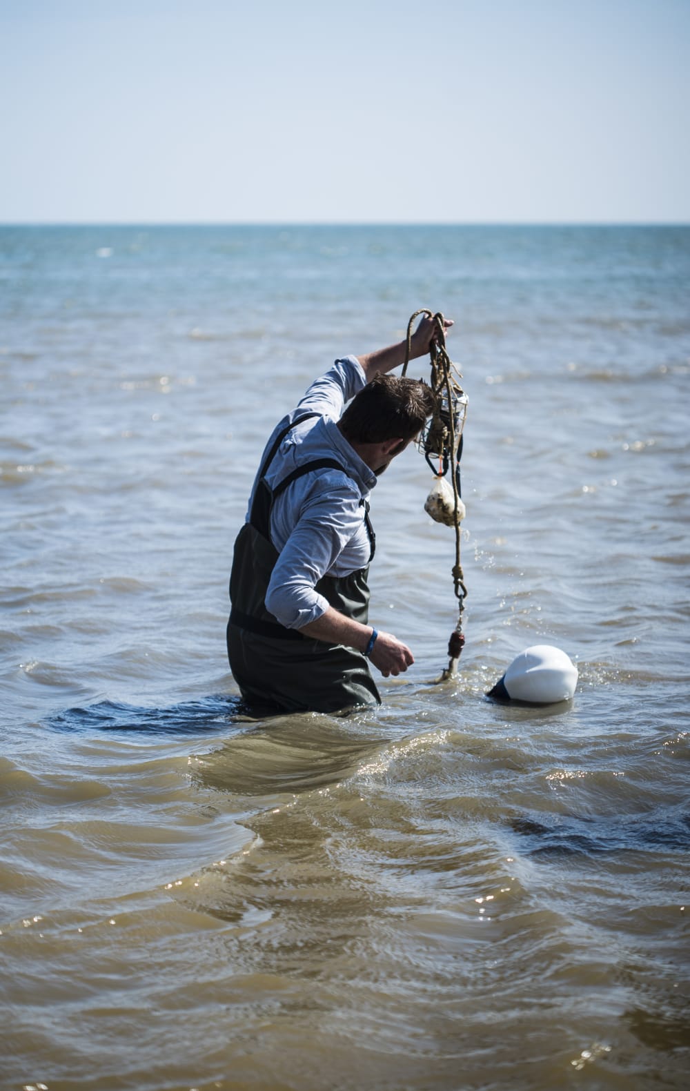 Man picking object out of sea
