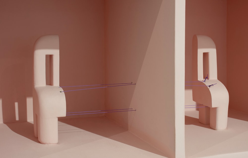 Close-up of a sculpture held together with purple thread.