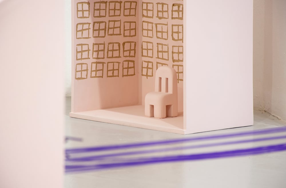 A sculpture of a house torn in two and connected by purple rope.