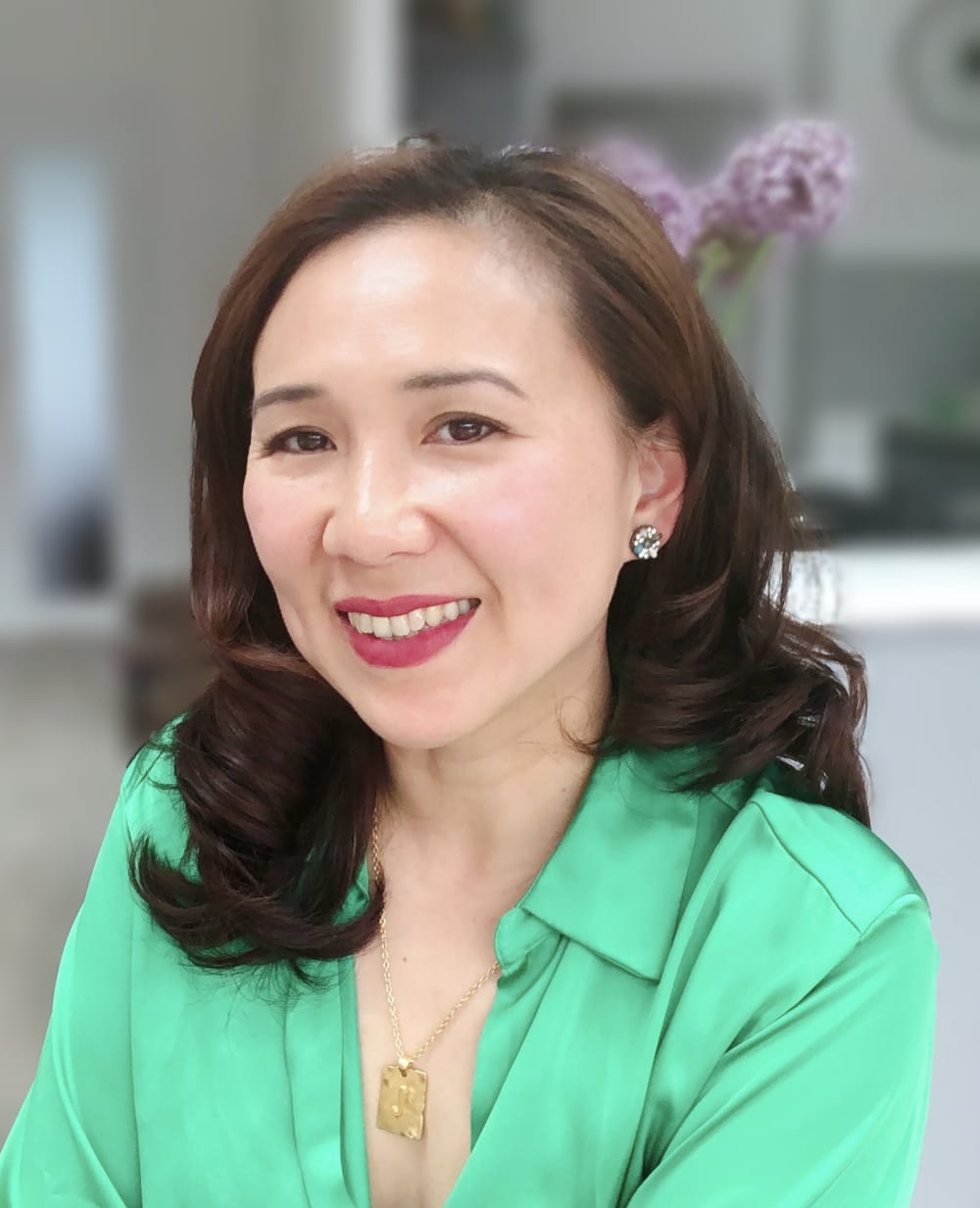 Headshot of Jasmine. She's wearing a bright green blouse and red lipstick. 