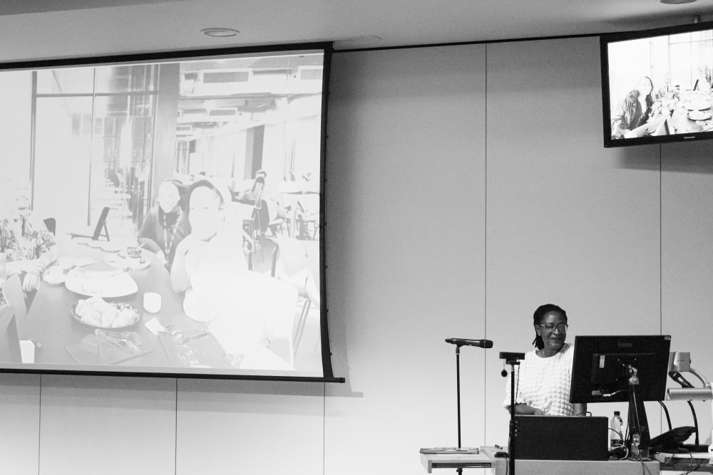 Woman presents at the front of event hall, standing behind a podium
