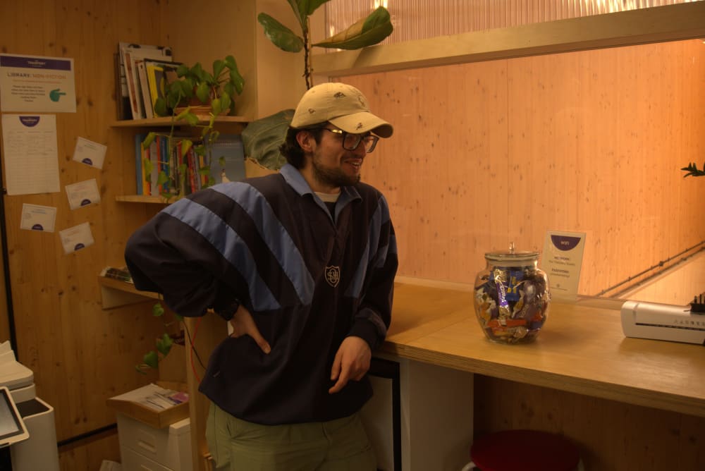 Man standing next to a shelf with a jar on top.