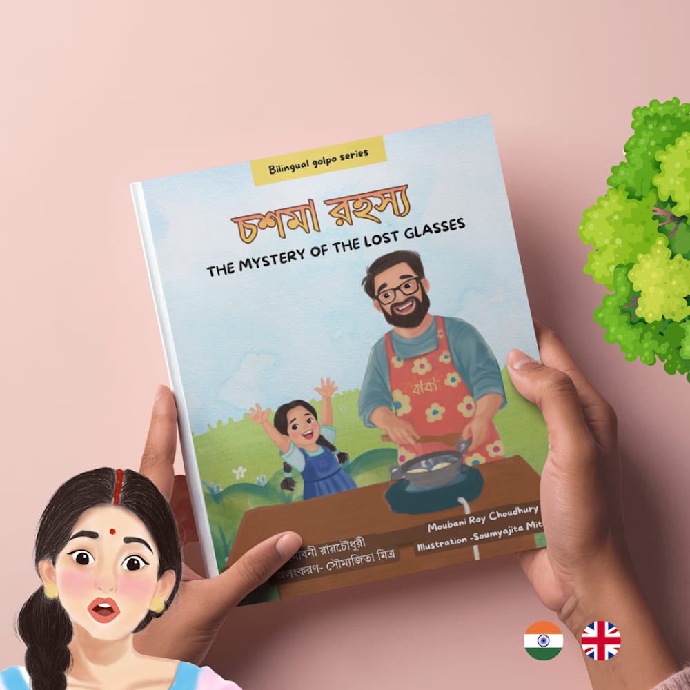 Two hands hold a bilingual children’s book titled Choshma Rohoshyo: The Mystery of the Lost Glasses against a soft pink background. The book cover features an illustration of an adult wearing glasses and an apron cooking at a table, alongside a child with raised arms in a grassy outdoor setting. The cover includes both Bengali and English text and notes the author, Moubani Roy Choudhury, and illustrator, Soumyajita Mitra. Decorative elements include a cartoon character in the bottom-left corner, a tree graphic in the top-right corner, and Indian and UK flags near the bottom-right corner, highlighting the book’s bilingual nature.
