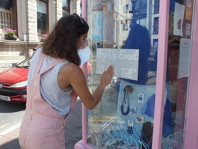A woman sticking a sign to a shop window.