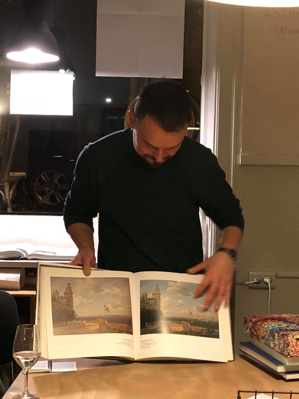 A man showing talking and showing a book