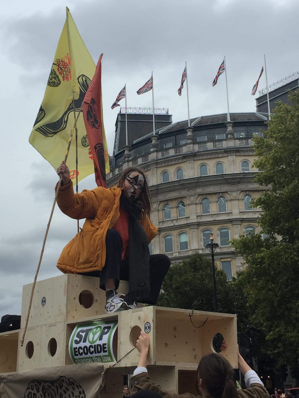 A woman sitting on top of a wooden structure at a protest