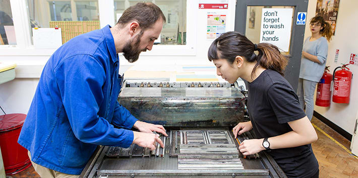 A technician assisting a student with typesetting in the Letterpress workshop.