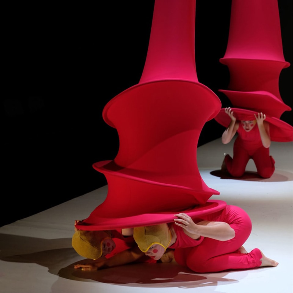 Performers peek out from underneath red costumes