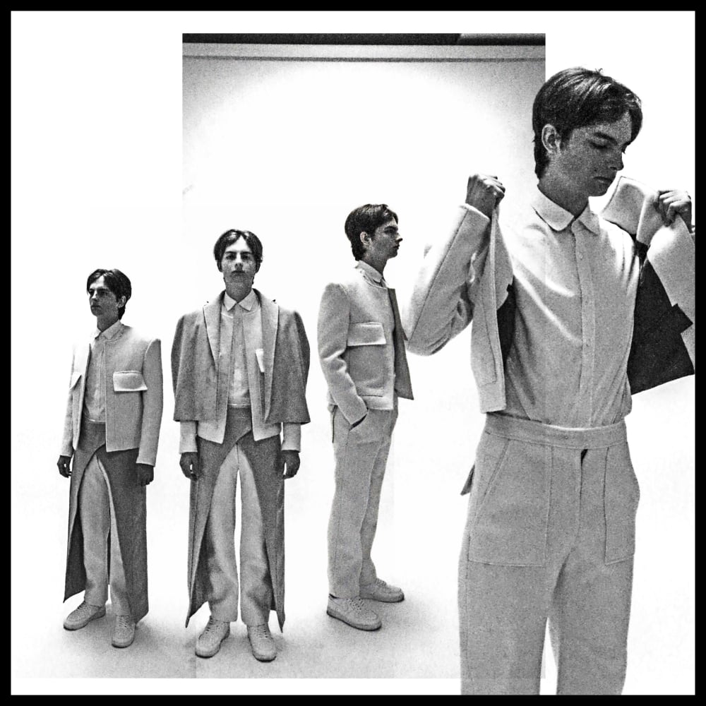 A black-and-white image of a line-up featuring a person wearing a tailored 3-piece suit