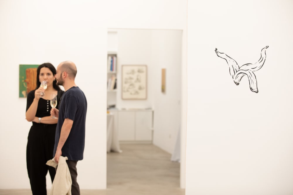 The focus is to right, on a black line drawing. 2 people stand to the left of the image, slightly out of focus. 