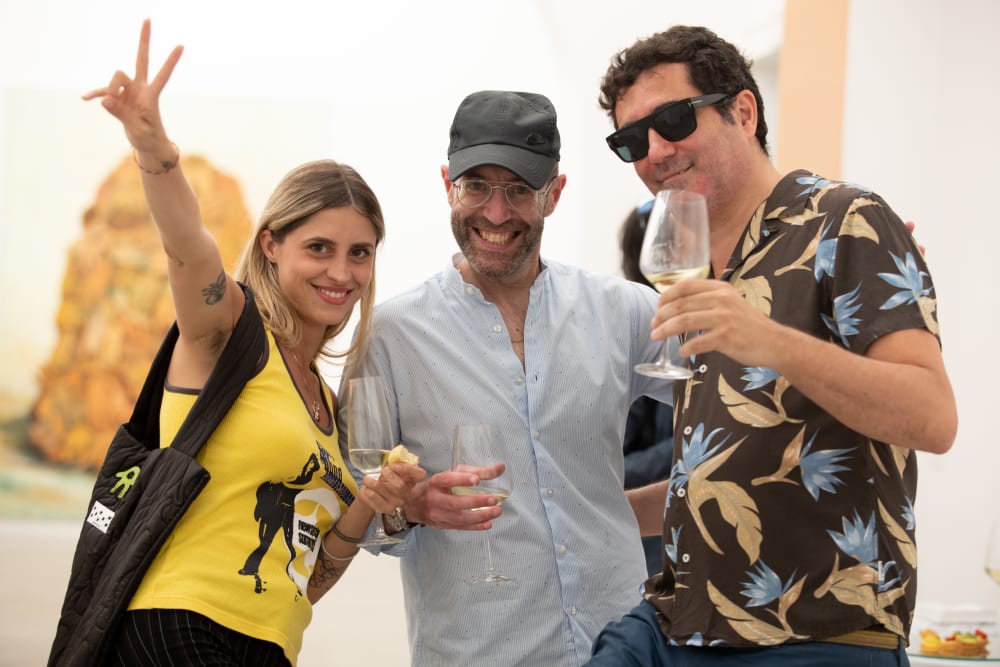 3 guests smiling to the camera. A woman wearing a yellow top is doing a peace sign in the air.