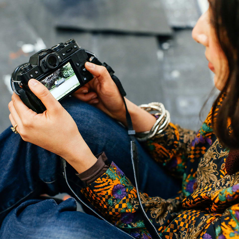 A student is viewing a photograph they have taken of a person on a bench on a camera screen. 