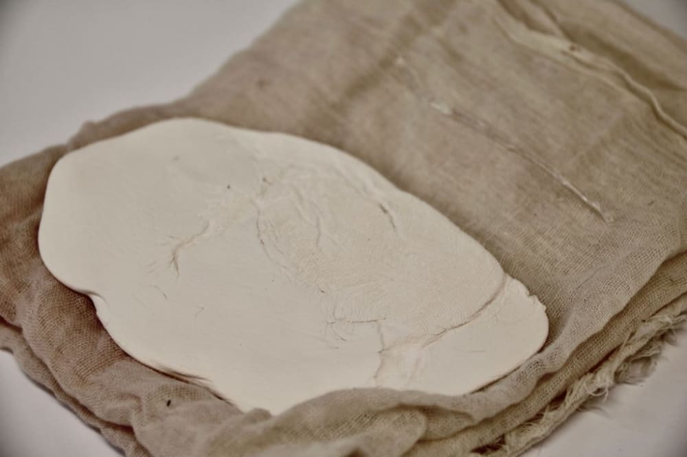 A white stone sculpture on a brown hessian bag