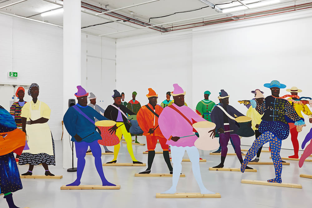 Large colorful painted cutouts of people in a white room.