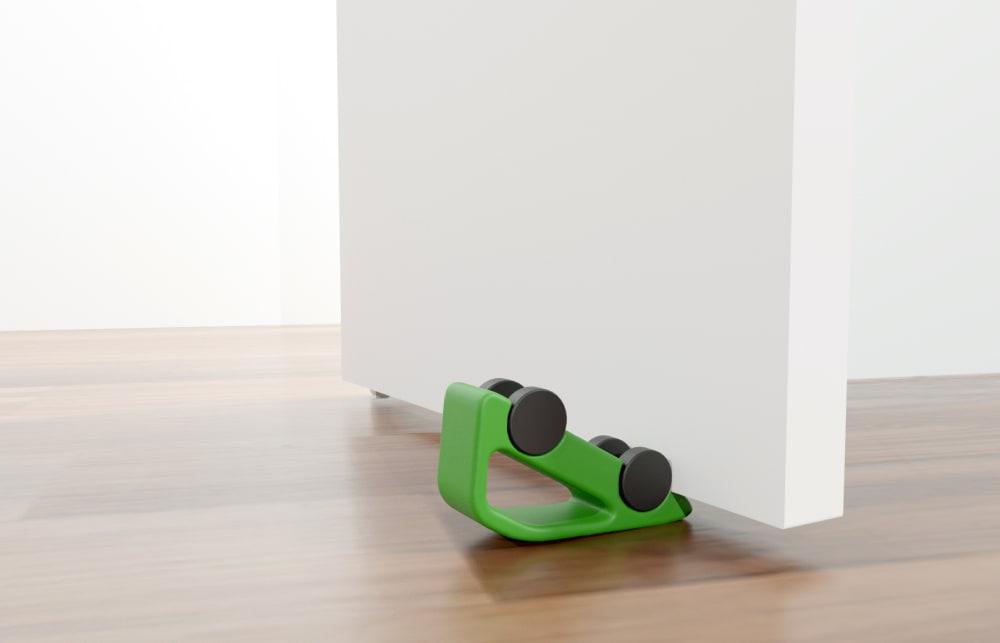 Upturned green toy car against white wall