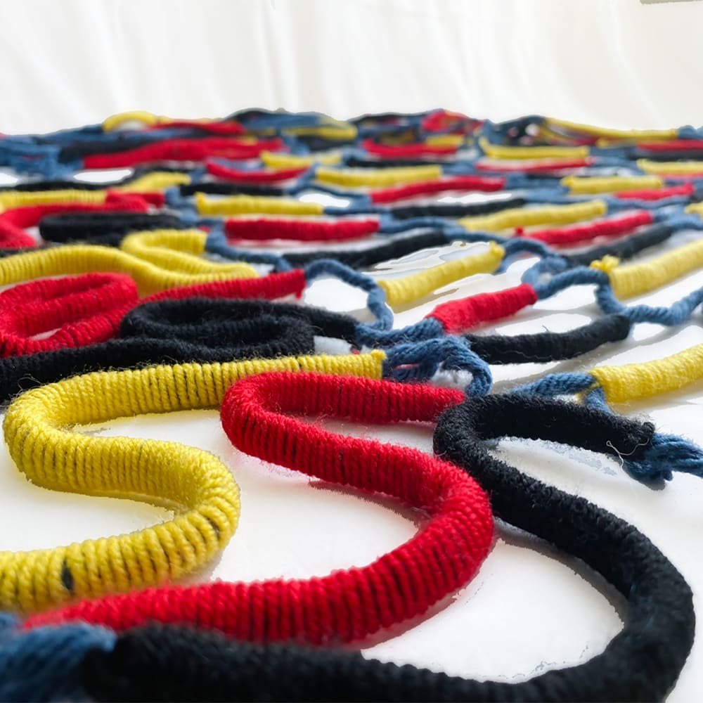 Close up photograph of final threads, black, yellow and red colours