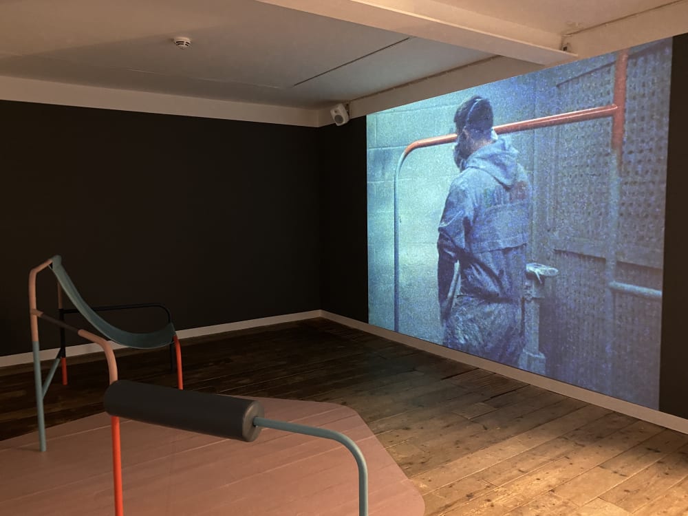 A large piece of work projected onto a wall with colourful sculptures in front of it