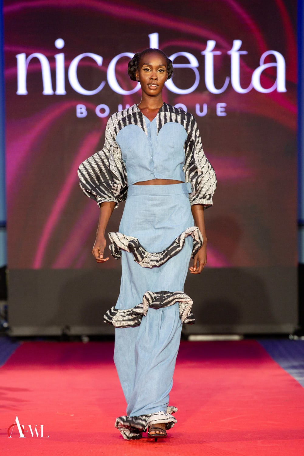 Woman walking red runway in a blue two piece. 