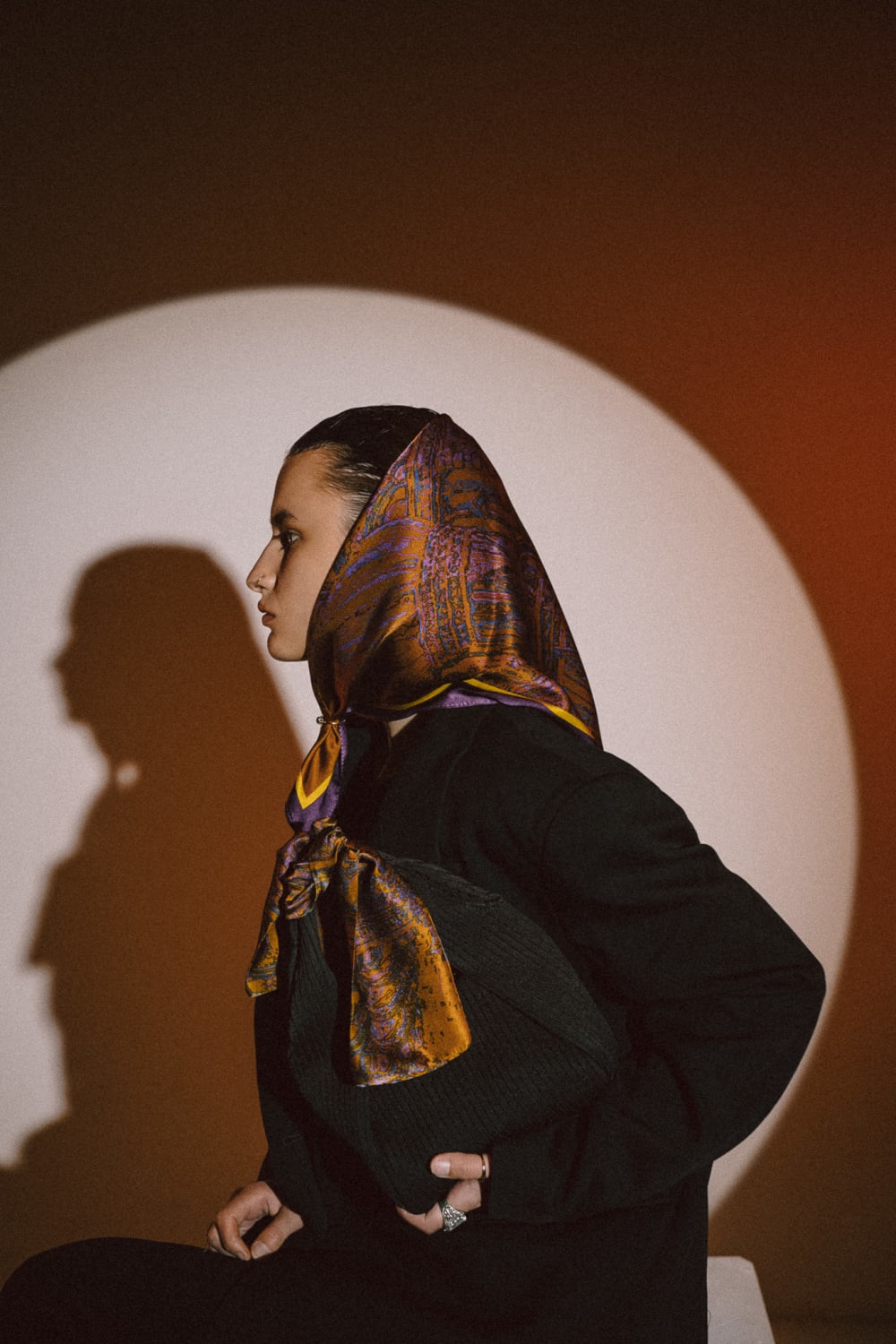 An image of a girl wearing a scarf and holding a bag with scarf tied to it