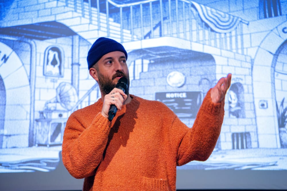 Mcbess talking into a microphone