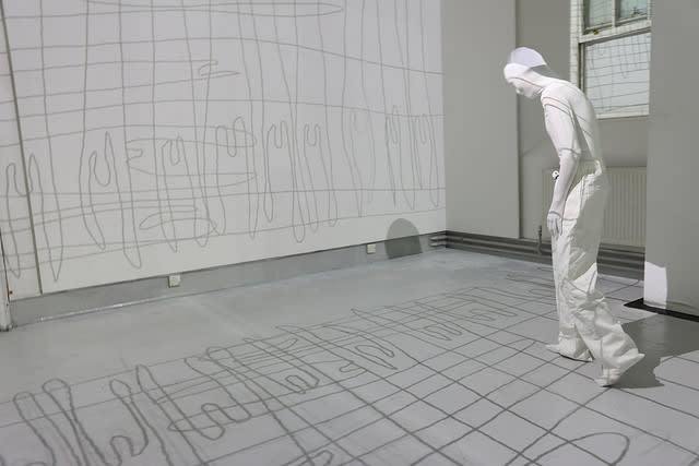 Figure all in white with their face covered walking around a white room.