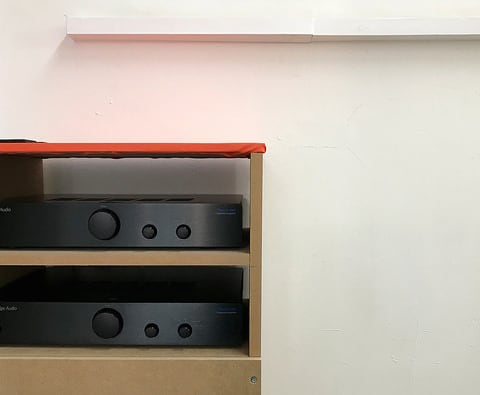 Two speakers on a shelf with a red top.