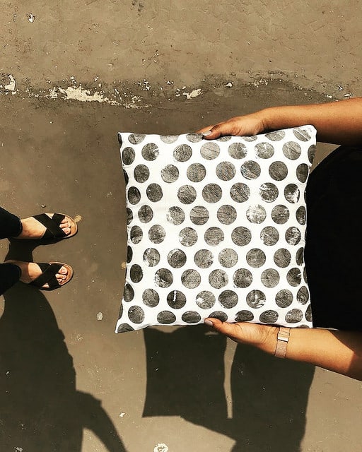 someone holding a white polka dot cushion