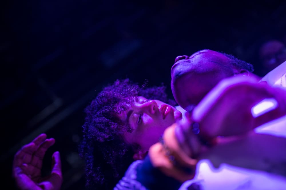 A man and woman dancing in purple light.