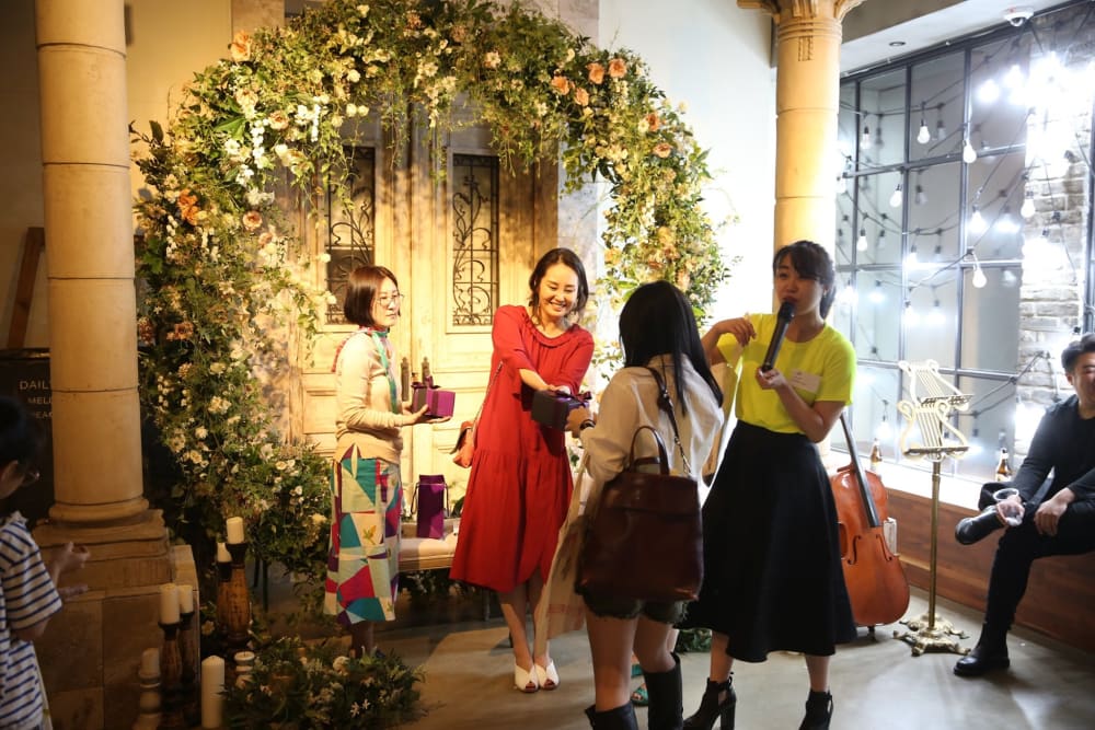 Landscape photo of 3 people, in front of a green flower arch