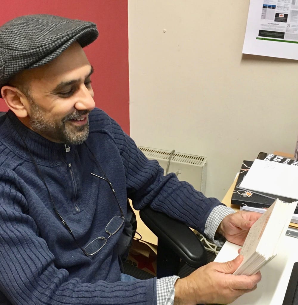 Man in flat cap sorting through postcards